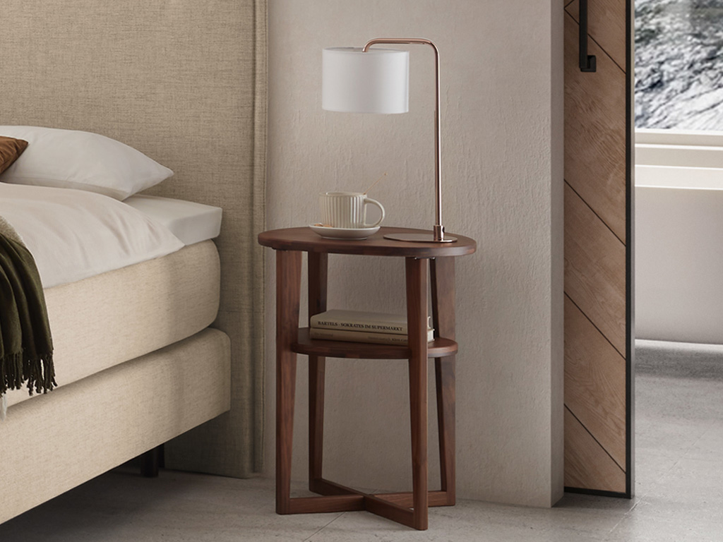 Hasena - Wilson Nachttisch (Beistelltisch) |  ø: 42 cm | Massivholz konfigurierbar brauner runder Holznachttisch mit rundem Einlegeboden eingefasst in ein Gestell stilvoll dekoriert an einem Bett in einem modernen Zimmer Wilson von Hasena