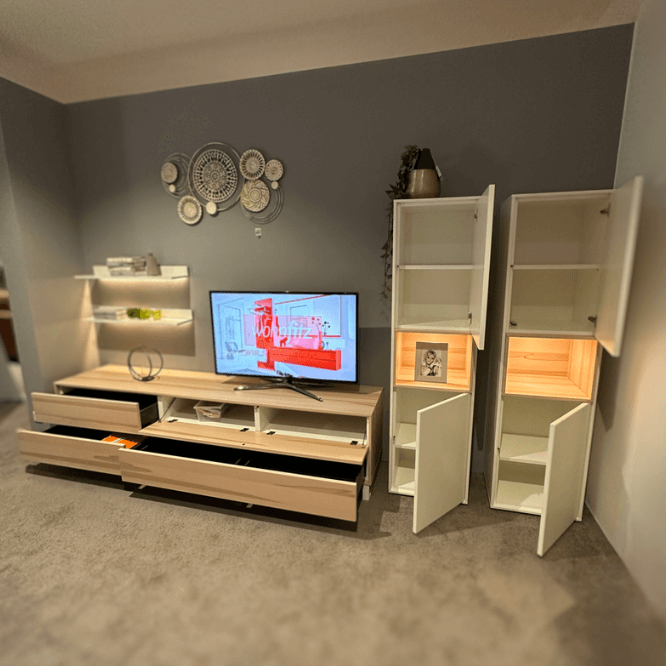 Ein stilvolles Wohnzimmer-Set bestehend aus einem TV-Tisch mit Schubladen, einem Fernseher und offenen Schrankvitrinen zur Lagerung und Dekoration.