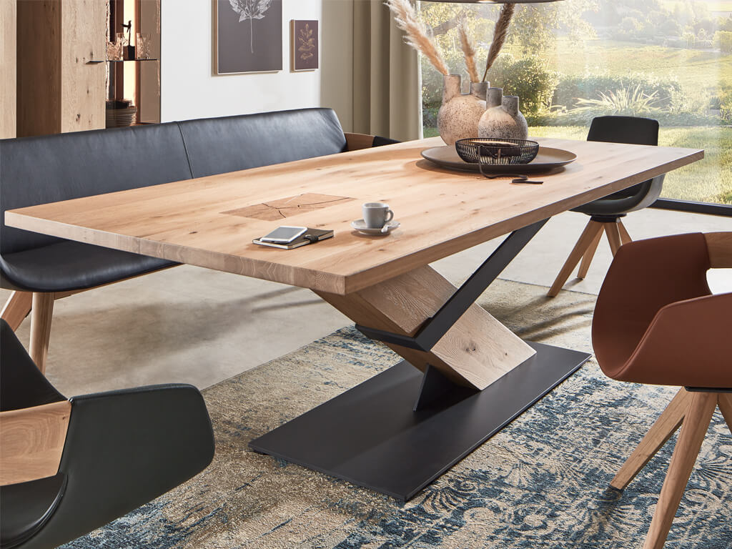 Schicker Holztisch mit modernem Metallgestell, umgeben von Stühlen und einer Bank in einem hellen, modernen Esszimmer mit dekorativen Elementen im Hintergrund.