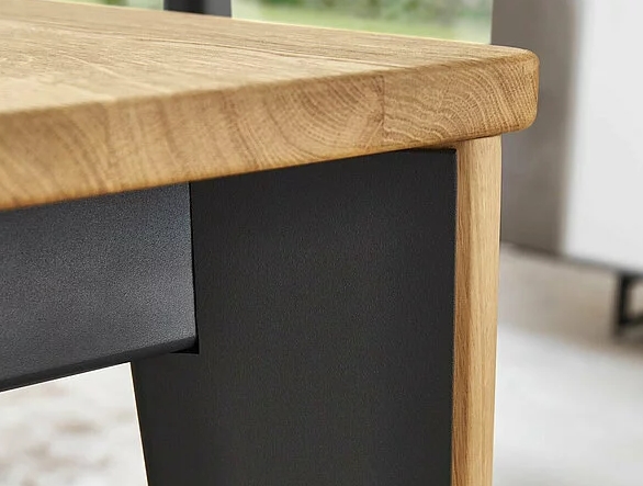 Nahaufnahme eines Tisches mit einer robusten Holzplatte und stabilen schwarzen Metallbeinen
