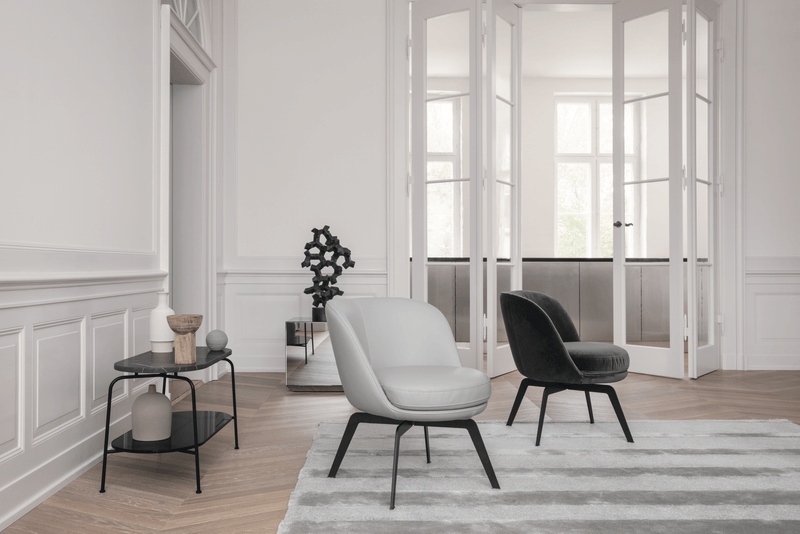 Ein elegantes Wohnzimmer mit zwei Designer-Sesseln auf einem gestreiften Teppich, einem Beistelltisch mit Dekoration und weißen Doppeltüren im Hintergrund.