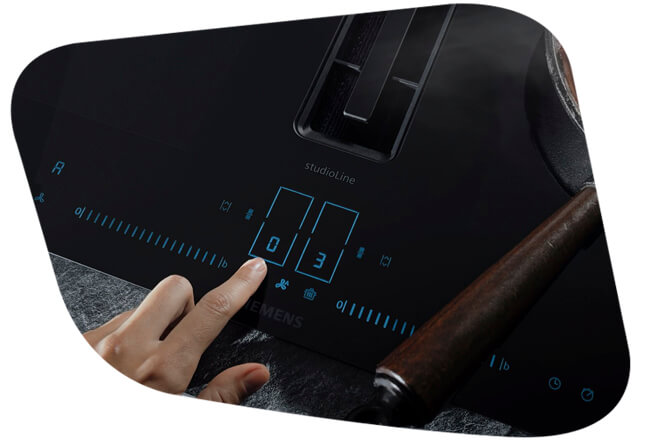 Finger, welcher auf dem Touchslider eines Siemens Induktionskochfelds ein Programm auswählt.