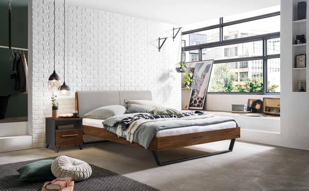Ein modernes Schlafzimmer mit einem Holzbett, Nachttisch, großer Fensterfront und stilvollen Dekorationen wie Hängeleuchten und Pflanzen.