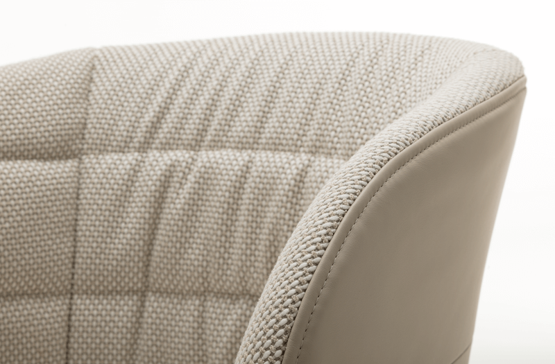 Detailansicht eines gepolsterten Stuhls mit Stoff und Leder in beige