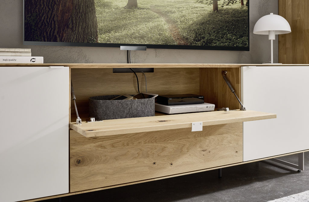 Detailaufnahme eines braun-weißen Lowboards mit geöffneter Medienklappe stilvoll dekoriert