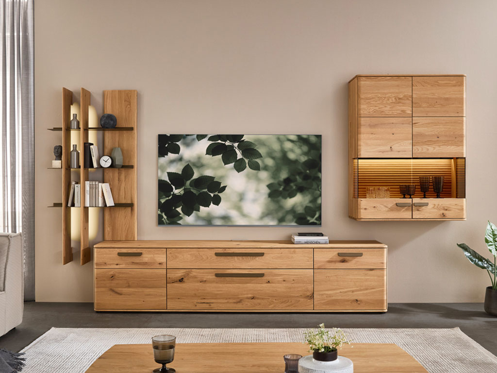 moderne Wohnwand aus Eiche mit einem großen Lowboard, beleuchtetem Regal und beleuchteter Hängevitrine stilvoll dekoriert in einem modernem Zimmer