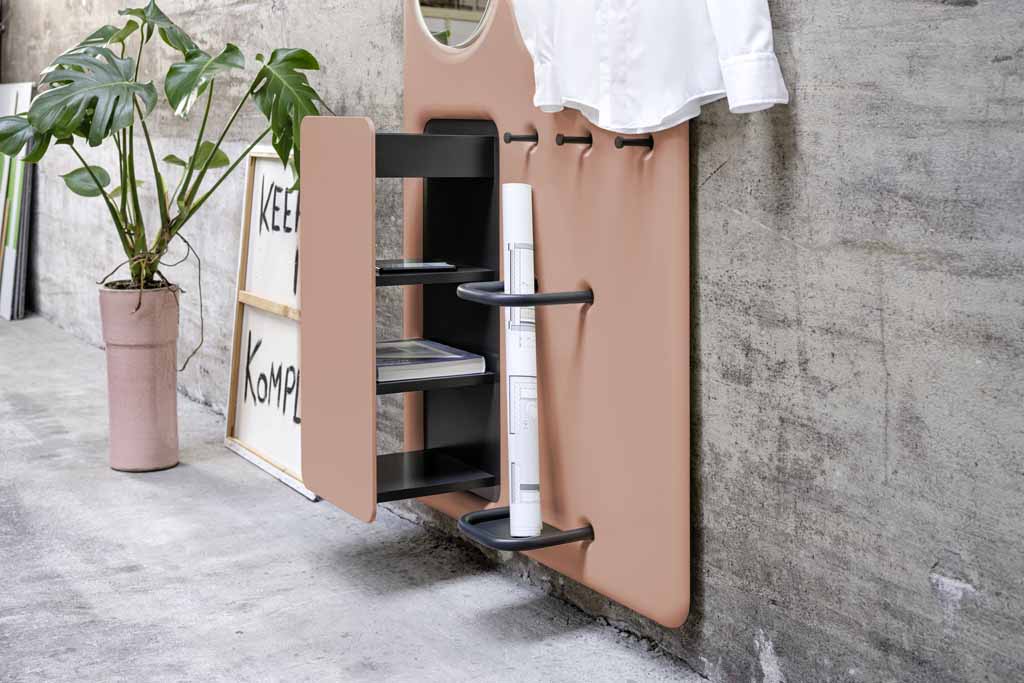 Ein stilvoller Wandorganizer in Braun mit Regal für Bücher und Zeitschriften, daneben eine Grünpflanze in einem rosa Topf vor einer Betonwand. Ideal für modernes Wohnen.