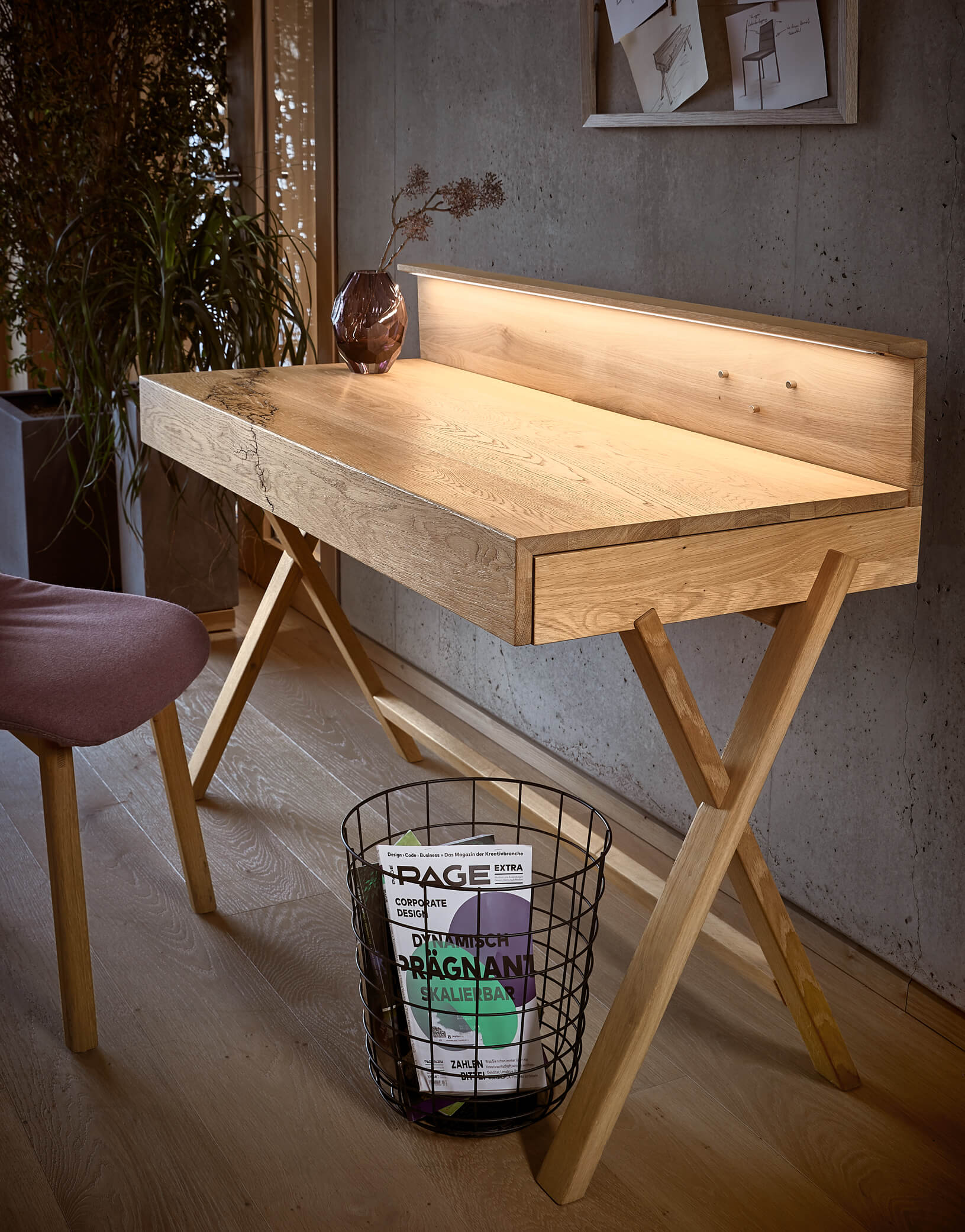 Moderner Holzschreibtisch mit LED-Licht, Vasen-Dekoration und Magazin im Papierkorb, in einem stilvoll eingerichteten Raum.