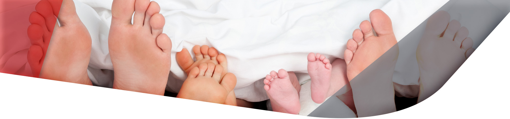 Füße einer Familie schauen unter der Bettdecke raus