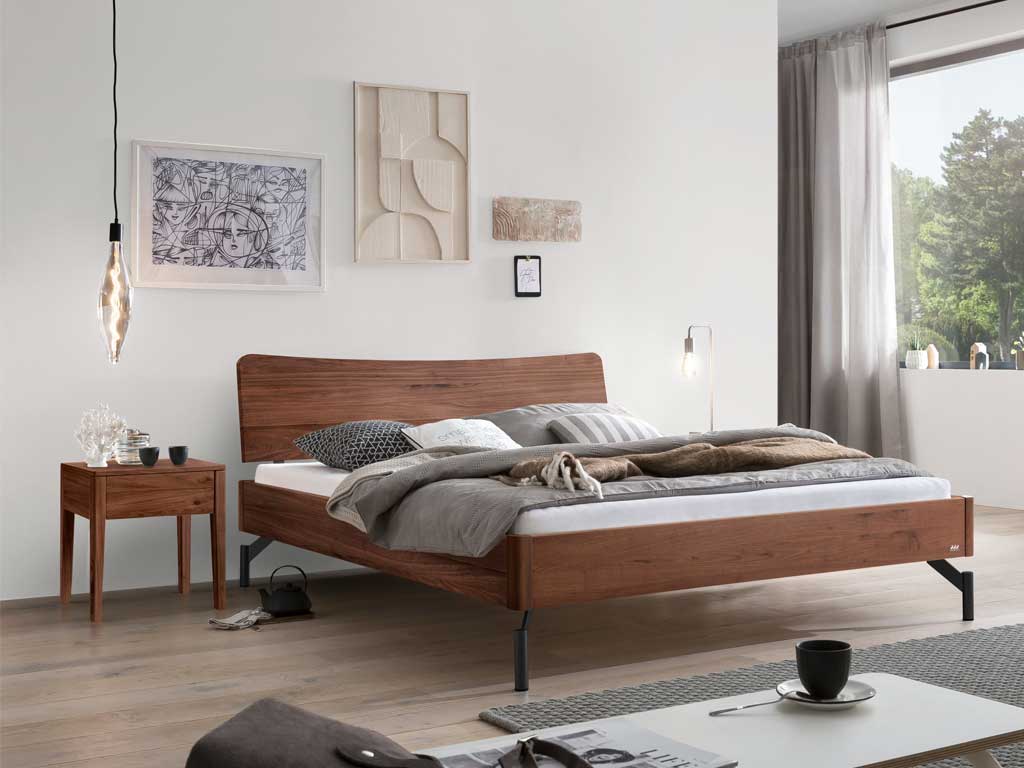Hasena -  Lounge Bett Albinia | Holzkopfteil Wave | Metallfuß Tondino | versch. Größen & Farben konfigurierbar braunes Holzbett mit Nachtisch in modernem Schlafzimmer