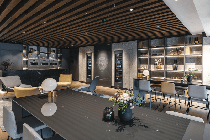 Ein moderner Besprechungsraum mit edlem Interieur, darunter ein großer Tisch, bequeme Stühle und dekorative Beleuchtung.