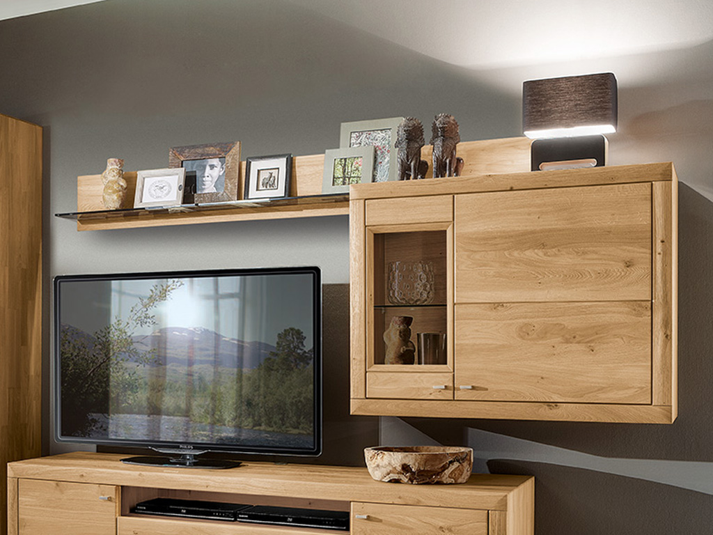 Wöstmann Aurum - Anbau L-Wandboard | Type 0143/0173/0203 | Wildeiche massiv | konfigurierbar Holzmöbel im Wohnzimmer mit Flachbildfernseher, Regalen mit Bilderrahmen und Lampe
