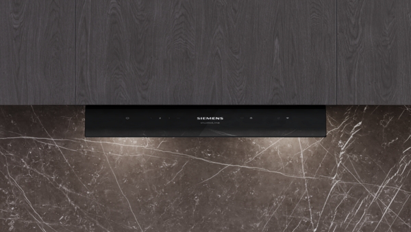 Bedienfeld der Dunstabzugshaube: Frontale Nahaufnahme der schwarzen Glasfläche der Siemens studioLine Dunstabzugshaube mit Touch-Bedienelementen und LED-Beleuchtung.