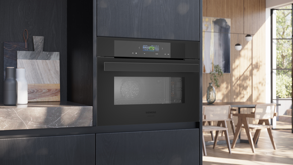 Eingebauter Siemens Studioline Backofen in schwarzem Design mit geschlossenem Sichtfenster und beleuchtetem Touch-Display in einer modernen, hellen Wohnküche.