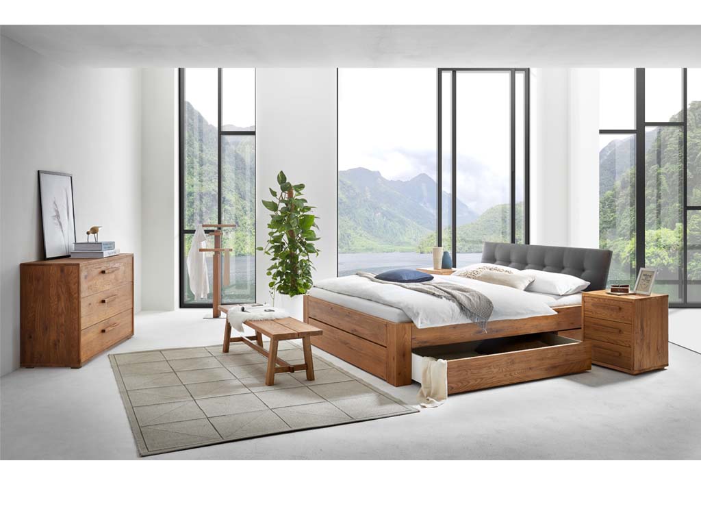 braunes Schlafzimmer in einem hellen Raum mit einem Bett mit Bettkasten und grauem Polsterkopftei einer Bank einem Stummen Diener einer Kommode mit drei Schubladen einer kleinen Kommode mit drei Schubladen stilvoll dekoriert Hasena