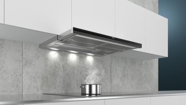 Edelstahl Dunstabzugshaube über dampfendem Kochtopf in moderner Küche