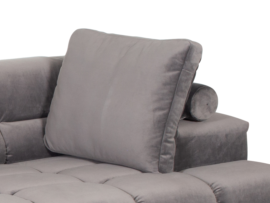 Nahaufnahme eines hellgrauen Samtsofas. Ein quadratisches Rückenkissen ist in die Rückenlehne des Sofas eingesetzt, und dahinter ist eine kleine zylindrische Nackenrolle sichtbar. Die Sofapolsterung hat ein gestepptes, quadratisches Muster.