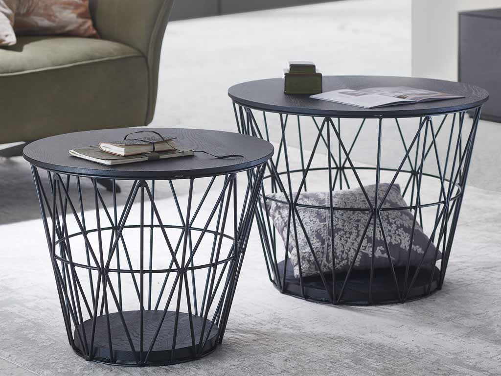 hartmann Naturstücke - Couchtisch, klein | 1071 | Kernesche anthrazit Zwei moderne Couchtische aus Metall mit dunkler Tischplatte und integrierter Ablage, dekoriert mit Büchern und Kissen, in einem stilvollen Wohnzimmer.