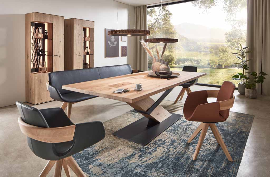 Elegantes Esszimmer mit großem Holztisch, modernen Stühlen und großen Fenstern mit Blick ins Grüne