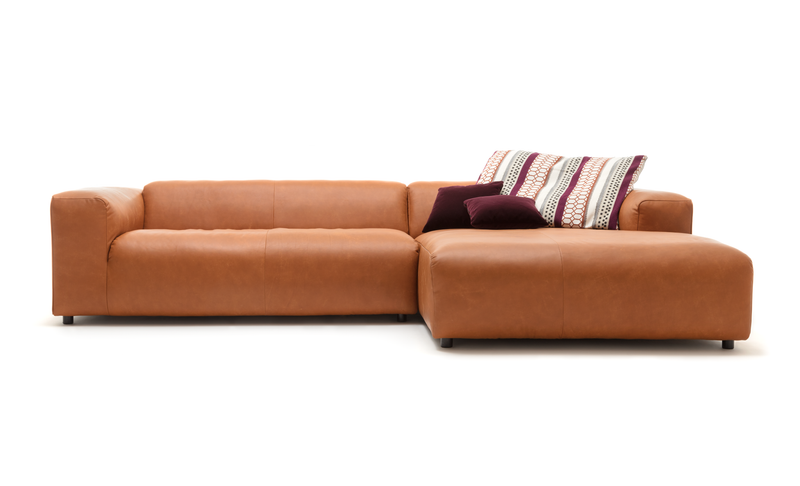 Elegantes braunes Ledersofa in L-Form mit zwei gemusterten Kissen und einem einfarbigen Kissen