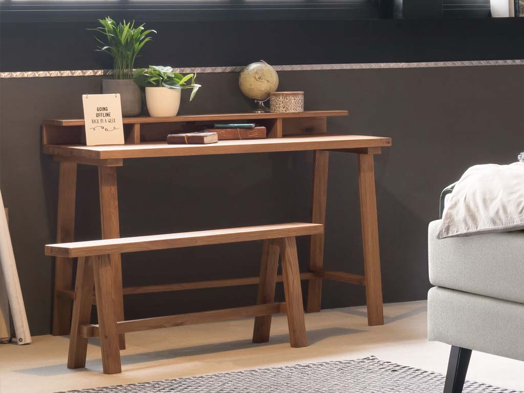 Sekretär und kleine Sitzbank aus Holz vor dunkler Wand stilvoll dekoriert