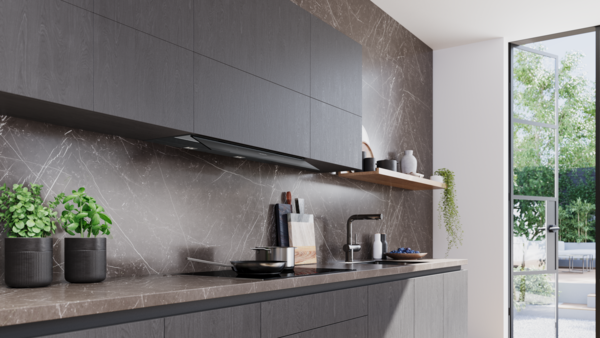 Moderne, dunkle Küche mit Marmor-Rückwand. Die Flachschirmhaube ist dezent unter den Oberschränken montiert; auf dem Induktionskochfeld steht eine Pfanne.