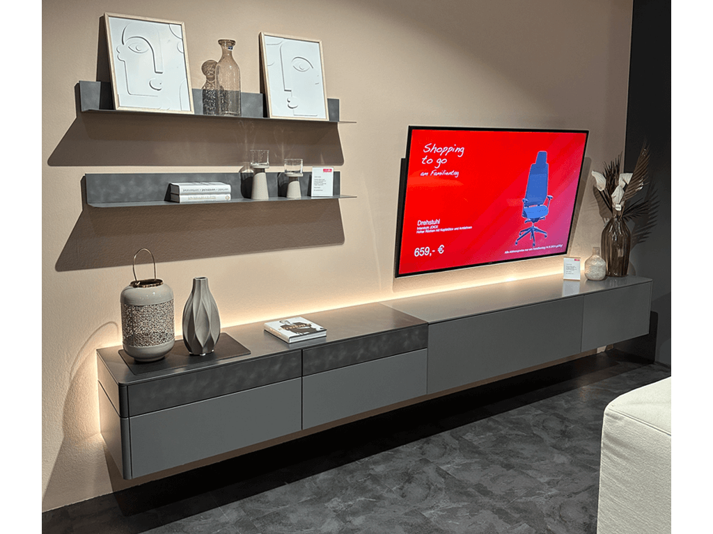 Sudbrock GOYA | Wohnwand Stilvolles Wohnzimmer-Setup mit wandmontiertem Fernseher, dekorativen Regalen und modernen Möbeln.