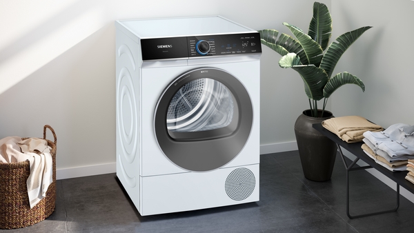 Weiße Waschmaschine in modernem Badezimmer mit Pflanze und gefalteter Wäsche