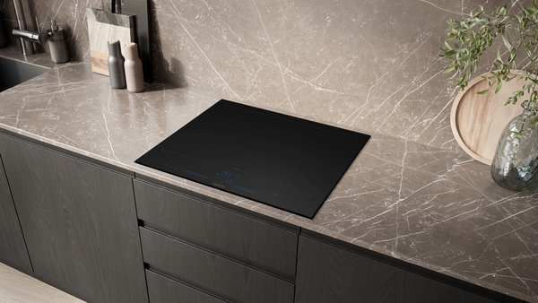 Siemens studioLine Induktionskochfeld EX67BNYV6E, eingelassen in eine dunkelbraune Marmor-Arbeitsplatte, umgeben von dunklen Holzschränken in einer modernen Küche.