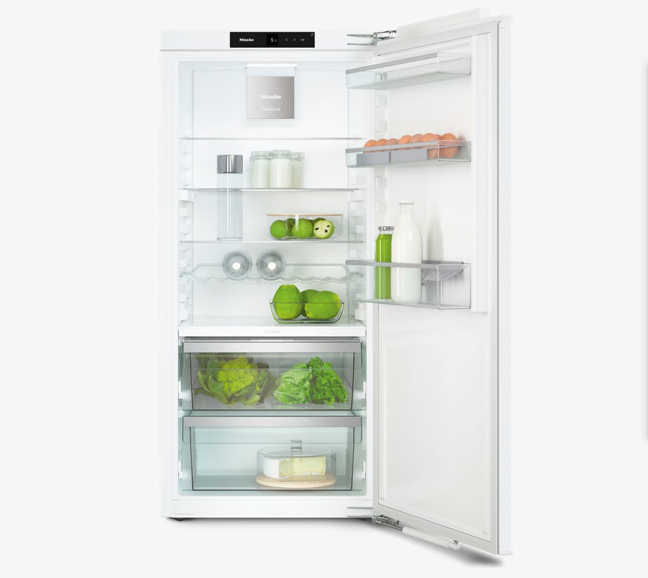 Der Miele Einbau-Kühlschrank K 7347 C mit geöffneter Tür, freigestellt auf weißem Hintergrund. Der Innenraum ist mit Lebensmitteln wie Gemüse, Milch, Eiern und Joghurt gefüllt und zeigt die flexiblen Glasablagen und die Frischeschubladen.