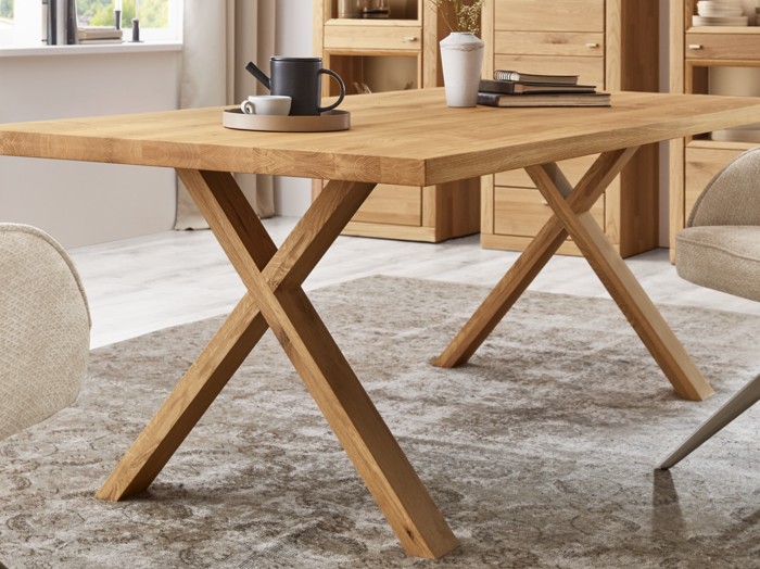 Nahaufnahme eines Holzesstisches mit X-Gestell stilvoll dekoriert in einem modernen Zimmer