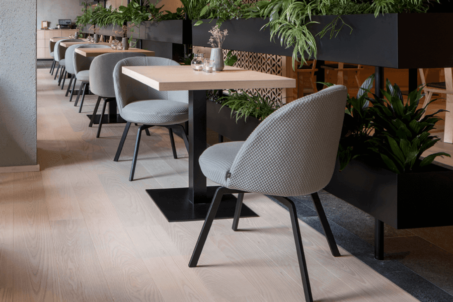 Cafe mit mehreren Holz Tischen und Polsterstühlen in hellgrau