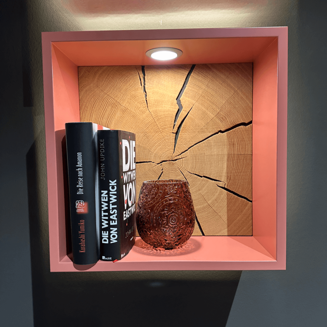 RMW DEVISO | Wandregal Ein stilvolles Regal mit zwei Büchern und einem verzierten Teelichthalter, beleuchtet durch eine LED-Lampe, vor einer hölzernen Hintergrundplatte.