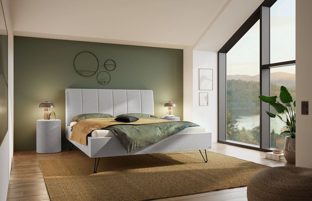 Hellgraues Polsterbett mit vertikal gestepptem Kopfteil und schwarzen Metallfüßen in einem modernen Schlafzimmer mit großer Fensterfront (KI-generiert)