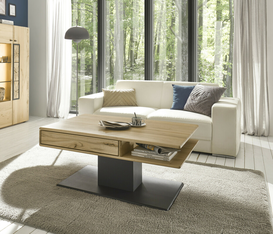 hartmann Knud - Couchtisch mit höhenverstellbarer Tischplatte | 1422 | Kernbuche massiv | B: 110 cm Elegant eingerichtetes Wohnzimmer mit hellen Möbeln, einem Holzcouchtisch und großen Fenstern mit Blick ins Grüne