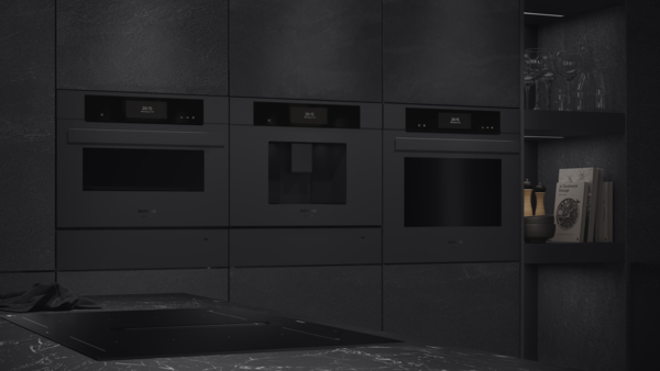 Drei schwarze Siemens studioLine Einbaugeräte, darunter ein Kaffeevollautomat und Backöfen, nahtlos integriert in eine dunkle, moderne Küchenwand mit Stein-Optik bei gedimmter Beleuchtung.
