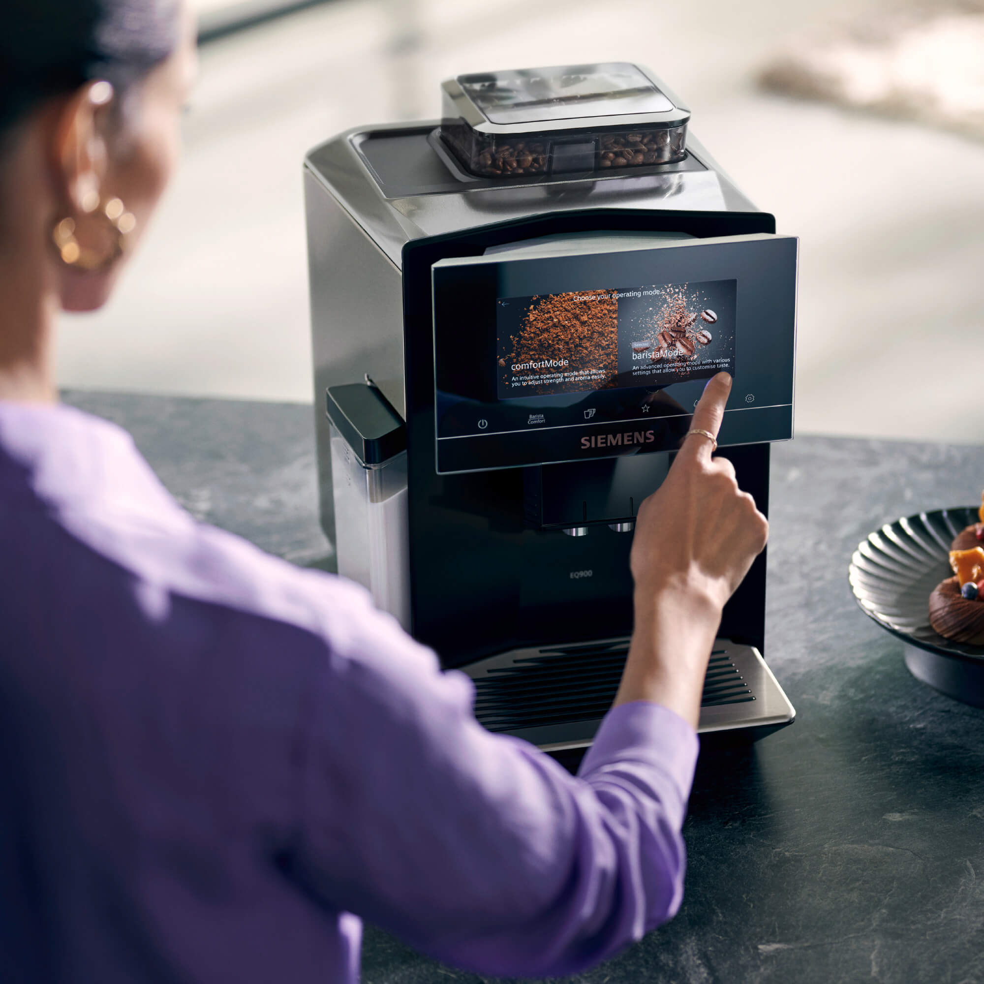 Frau tippt auf freistehenden Siemens Kaffeevollautomaten.