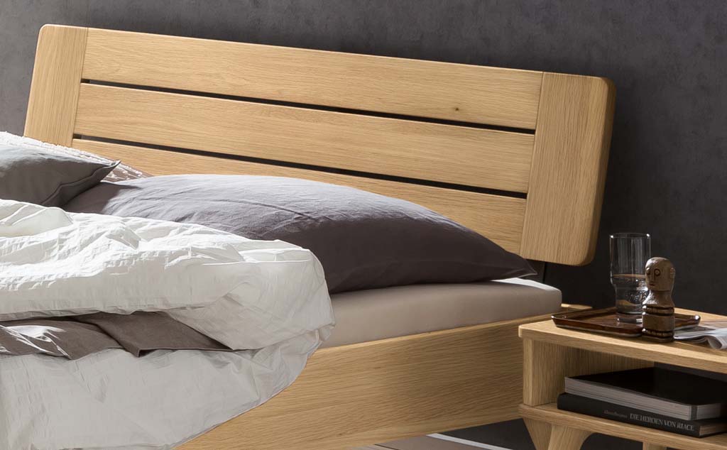 Detailaufnahme eines Holzbettes mit Holzkopfteil und Bettzeug