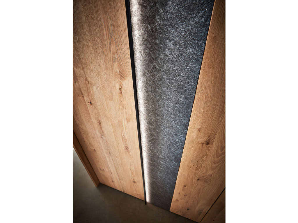 Detailaufnahme einer braunen Schranktüre mit grauen Griffleisten und grauem horizontal beleuchtetem Akzent