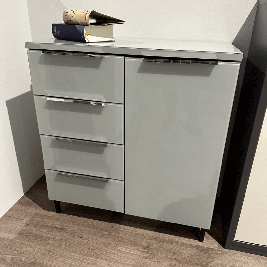 Moderner grauer Schrank mit mehreren Schubladen, darauf liegen Bücher