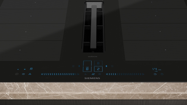 Detailansicht eines Siemens Induktionskochfelds mit integriertem Dunstabzug und Touch-Bedienfeld auf einer Marmorarbeitsplatte