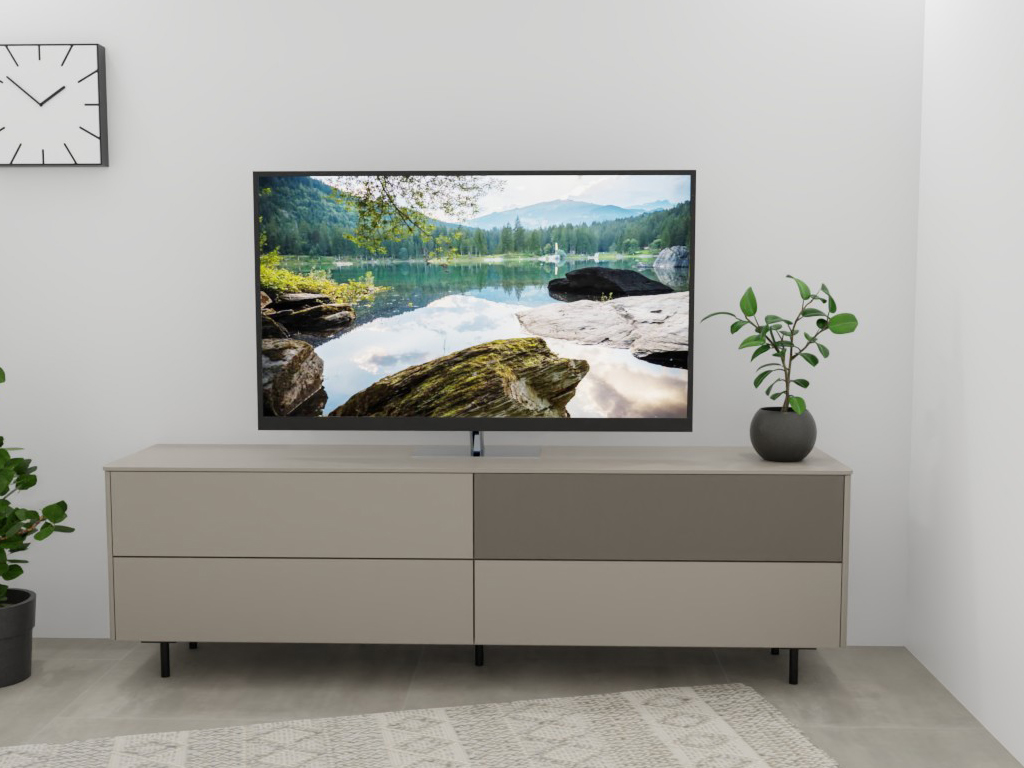 Sudbrock Goya - Lowboard mit Lochblechklappe | 2 Schubladen, 2 Klappen | B: 205,2 cm | Lack muschelgrau Ein stilvolles Wohnzimmer mit einem modernen Sideboard, darauf steht ein Fernseher, der eine Landschaft zeigt. Links steht eine Pflanze und eine Wanduhr hängt an der Wand.