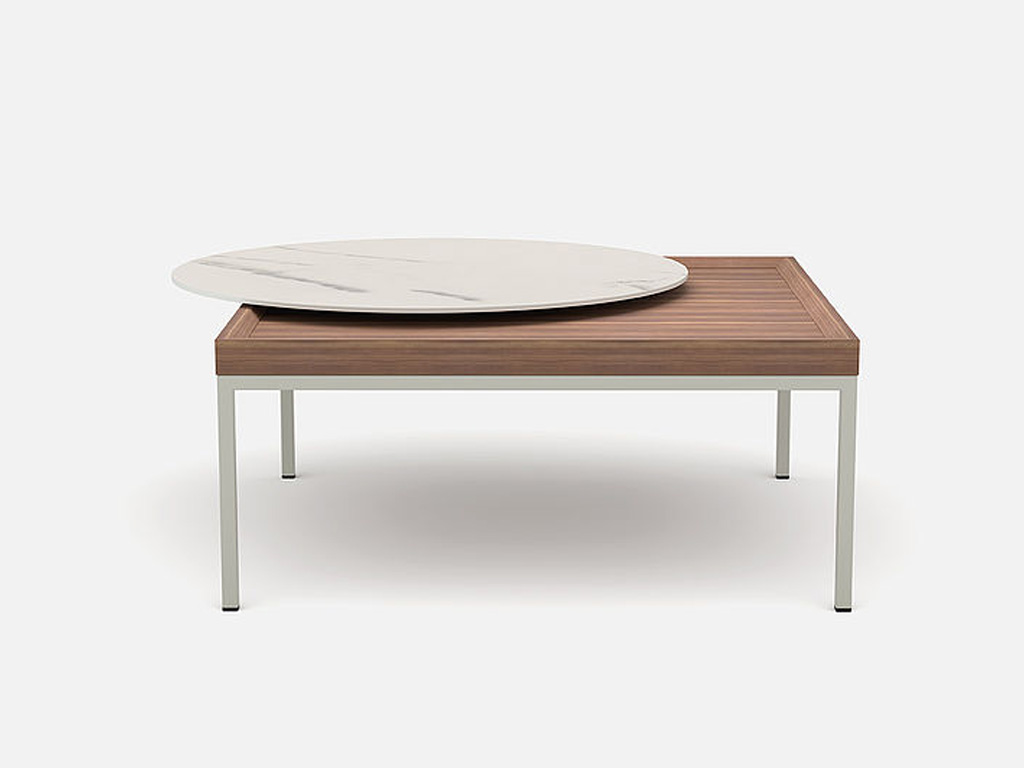 eckiger brauner Couchtisch mit hellem Gestell und einer runden beigen aufliegenden Platte vor grauem Hintergrund