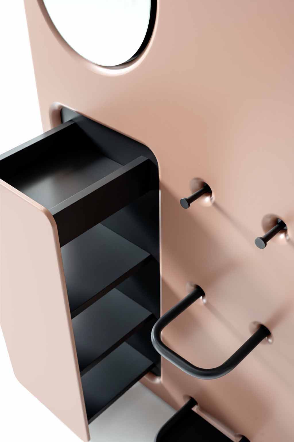Detailaufnahme eines modernen Schranks in Rosa mit einem runden Spiegel und schwarzen Regalen