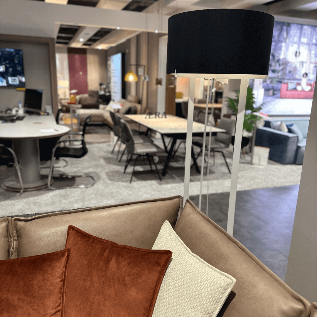Ein harmonisch eingerichtetes Wohnzimmer mit einer eleganten Stehlampe, einem komfortablen Sofa und geschmackvollen Kissen, umgeben von einem modernen Essbereich.