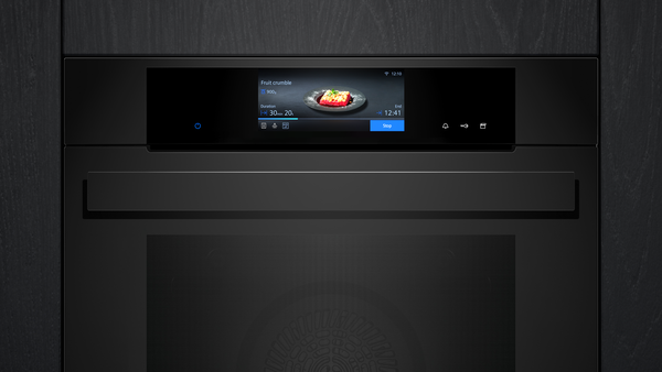 Nahaufnahme des digitalen Displays eines schwarzen Siemens Einbaubackofens, das den Fortschritt eines „Fruit crumble“ anzeigt.