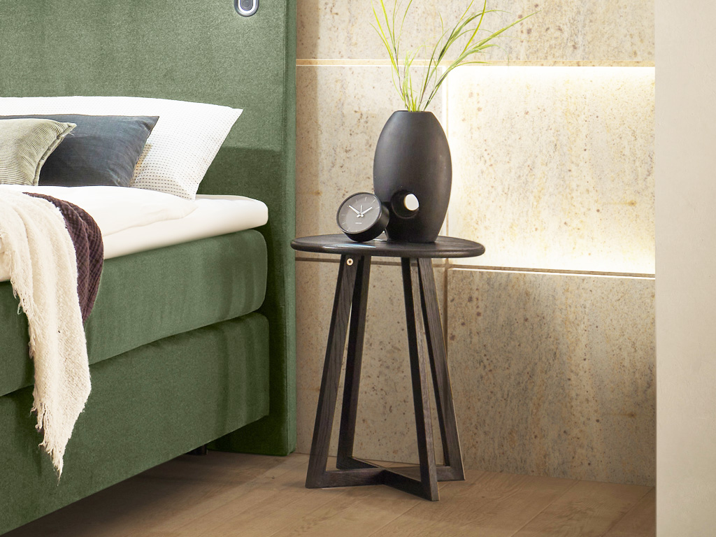 Hasena - Roy Nachttisch (Beistelltisch) |  ø: 42 cm | Massivholz konfigurierbar brauner runder Holznachttische auf Gestell stilvoll dekoriert an einem Bett in einem modernen Zimmer Roy von Hasena