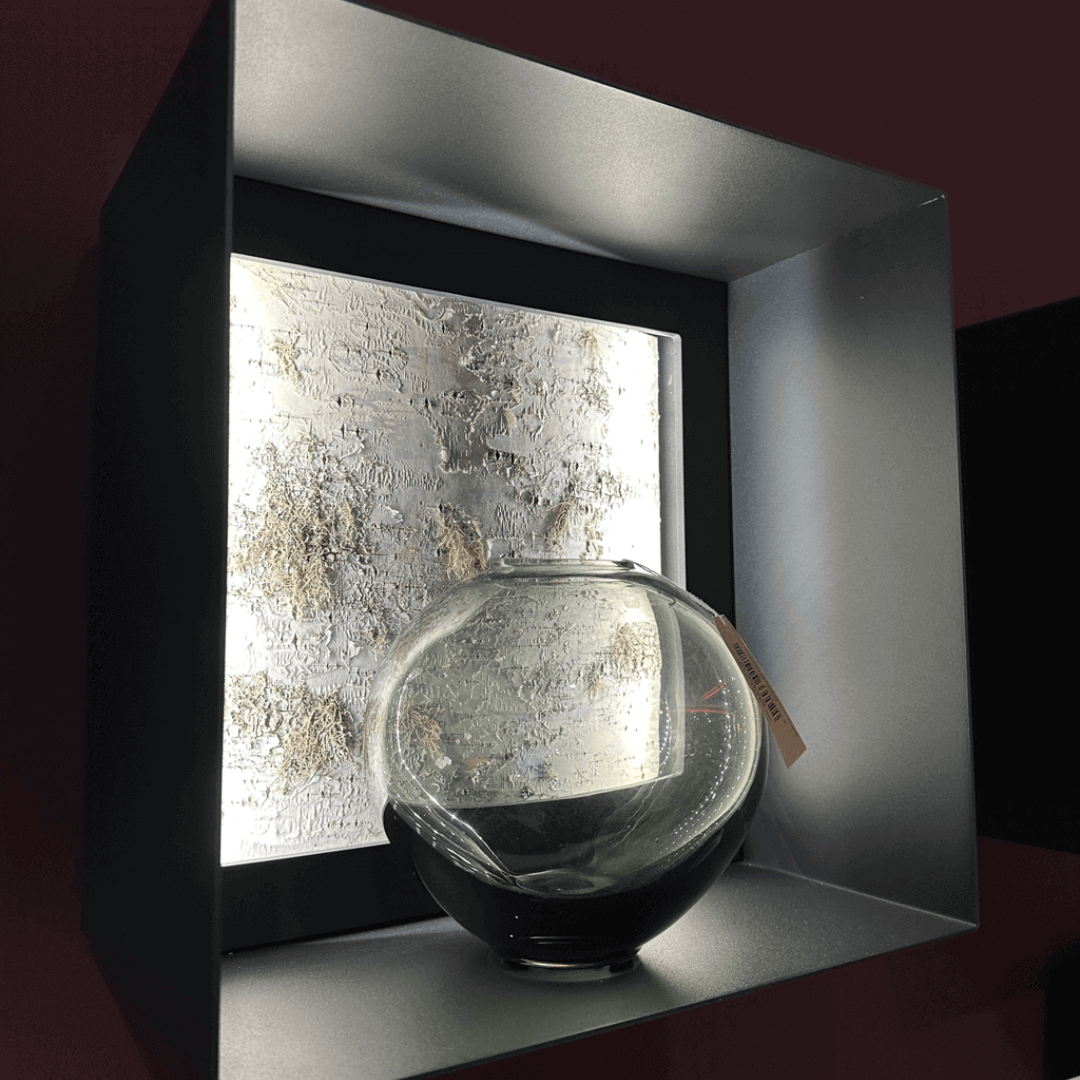 Elegante Glasvase vor strukturiert beleuchtetem Wandelement