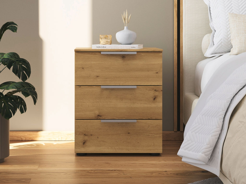 grauer nachttisch mit schwarzen griffen und mit drei schubkästen platziert neben einem bett in einem modernen zimmer stilvoll dekoriert