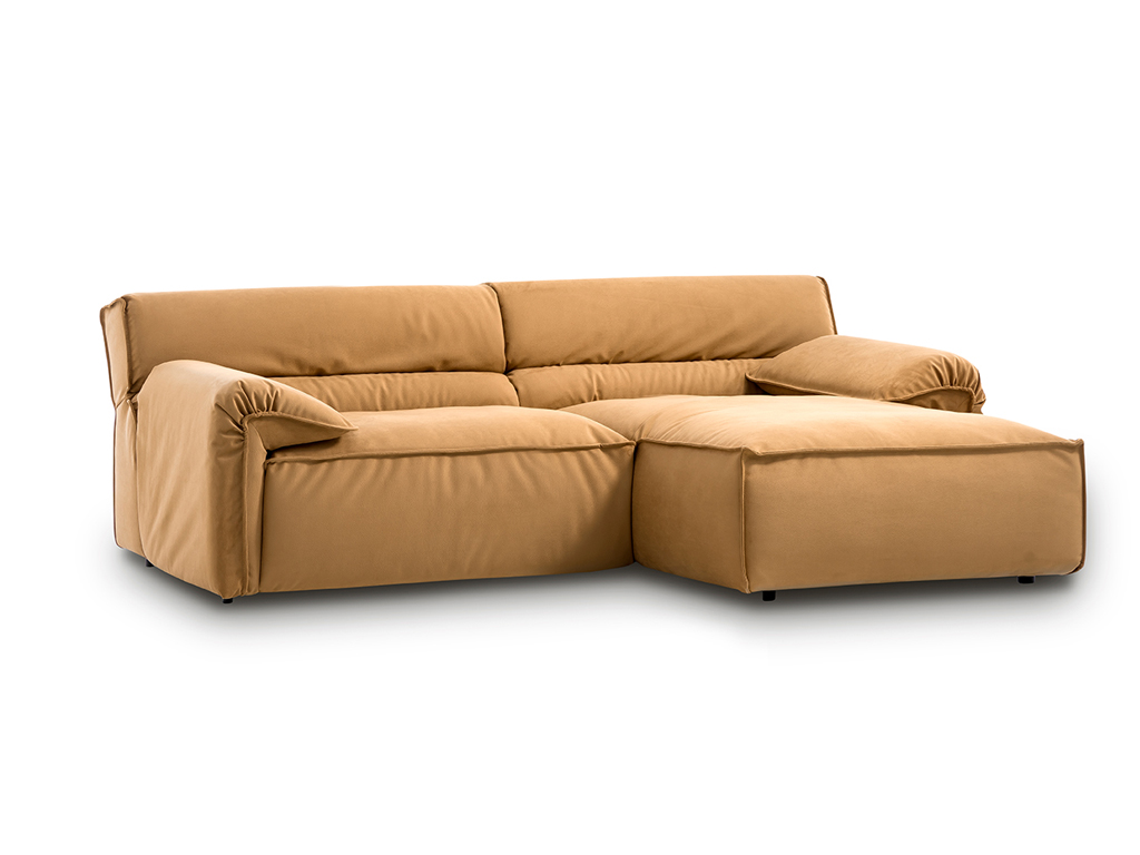 Ein modernes Ecksofa in senfgelbem Stoff mit voluminösen Kissen und einer Chaiselongue auf der rechten Seite, vor weißem Hintergrund.
